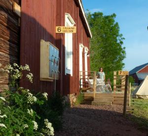 un homme assis sur la terrasse couverte d'une grange rouge dans l'établissement FARM LIVING, à Gottby