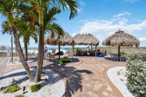 - une terrasse avec des tables et des parasols en paille sur la plage dans l'établissement 201 Sandy Shores Condos, à St. Pete Beach