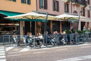 eine Gruppe von Menschen, die an einem Tisch mit Sonnenschirmen sitzen in der Unterkunft Padova Suites C20 in Padua