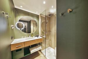 a bathroom with a shower and a sink and a mirror at H+ Hotel Frankfurt Eschborn in Eschborn