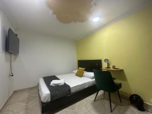 a small bedroom with a bed and a chair at Aloja-T en zona centrica de Armenia in Armenia