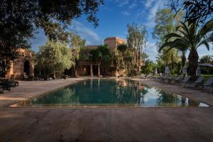 Villa Al Assala Palmeraie في مراكش: مسبح في حديقة فيها كراسي واشجار