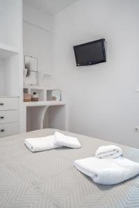 um quarto branco com uma cama com duas toalhas em ΚΑΤΟΙΚΙΑ ΜΙΝΙ ΠΙΣΙΝΑ ΜΠΡΟΣΤΑ ΣΤΗ ΠΑΡΑΛΙΑ 4-Larerooms 4 em Kythnos