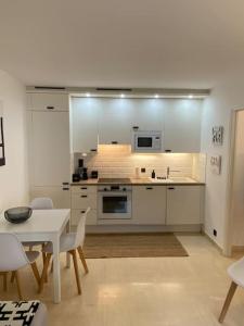 a kitchen with white cabinets and a table and chairs at T2 avec Terrasse et Jardin in Cannes