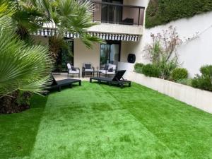 a backyard with green grass and chairs and a building at T2 avec Terrasse et Jardin in Cannes