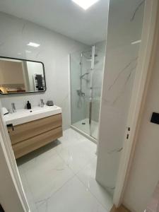 La salle de bains blanche est pourvue d'un lavabo et d'une douche. dans l'établissement T2 avec Terrasse et Jardin, à Cannes