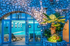 an entry to a building with a pool and a palm tree at Hotel Zlatni Lav in Martinšćica