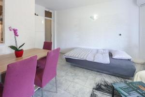 um quarto com uma cama, uma mesa e cadeiras roxas em Apartman Vito em Bakar