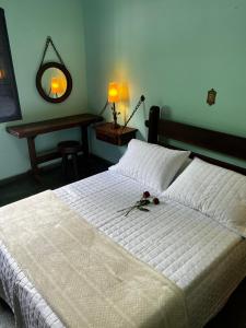 ein Schlafzimmer mit einem weißen Bett mit Blumen darauf in der Unterkunft Chácara das Araras in Lindóia