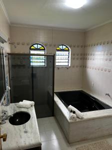 ein Badezimmer mit einer großen Badewanne und einem Waschbecken in der Unterkunft Chácara das Araras in Lindóia