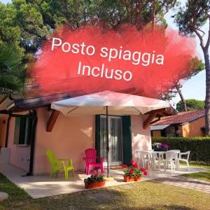 ein Haus mit bunten Stühlen und einem Regenschirm in der Unterkunft Villette Susanna in Lignano Sabbiadoro