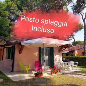 a house with colorful chairs and an umbrella at Villette Susanna in Lignano Sabbiadoro