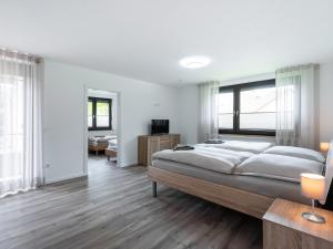 a bedroom with a large bed with white walls and wooden floors at Haus Laura in Bad Zwischenahn