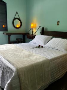 1 Schlafzimmer mit 2 Betten mit weißer Bettwäsche und einem Spiegel in der Unterkunft Chácara das Araras in Lindóia