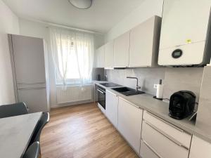 una cucina con mobili bianchi e pavimento in legno di 130qm - 2 Apartments side by side - free parking - city - MalliBase Apartments ad Hannover Altre 13 foto