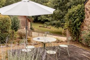 a table and chairs with an umbrella in a garden at Eco-Gîte La Métairie Saint-Michel de Quinipily By KEROUZEC in Baud