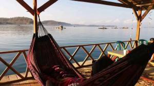 a couple of hammocks on a pier next to the water at Ekas beach floating room and restaurant in Ekas
