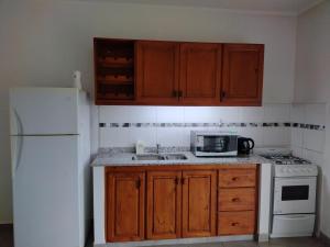 uma cozinha com armários de madeira e um frigorífico branco em La casita de Isa em Gualeguay