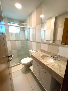 a bathroom with a toilet and a sink and a mirror at Cobertura Luxo Sophia I - Orla Praia Grande in Arraial do Cabo