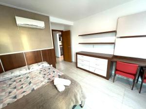 a bedroom with a bed and a desk and red chairs at Cobertura Luxo Sophia I - Orla Praia Grande in Arraial do Cabo