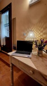 un ordenador portátil sentado en una mesa con una lámpara en Nel vicolo dei Baci - Casa vacanze al Bacio en Spello