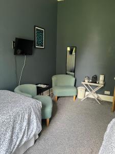 a bedroom with two beds and a chair and a mirror at Glenaldor House B&B in Dumfries