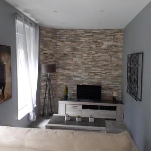 ein Wohnzimmer mit einem TV und einer Ziegelwand in der Unterkunft Gite d'ardin in Vrigne-aux-Bois