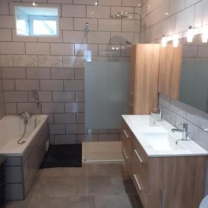ein Badezimmer mit zwei Waschbecken, einer Badewanne und einem Tubermott in der Unterkunft Gite d'ardin in Vrigne-aux-Bois
