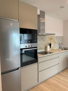 a kitchen with a stainless steel refrigerator and white cabinets at NUEVO Loylla Niembro a 500 m de la playa in Niembro