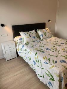 a bed with a floral comforter and pillows in a bedroom at NUEVO Loylla Niembro a 500 m de la playa in Niembro