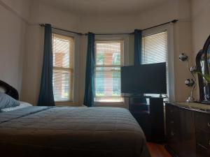 um quarto com uma cama e uma televisão de ecrã plano em Crsytal Chateau Room Rental em Brooklyn