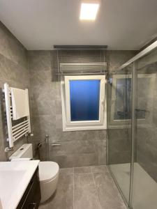baño con ducha y aseo y ventana en Apartamentos modernos Residencial el Pinar en Liencres