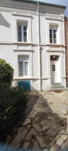 a white building with a door and a stone driveway at L'esperance 2 in Haybes