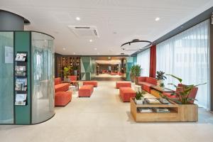 a lobby of a hospital with orange chairs at H+ Hotel Frankfurt Eschborn in Eschborn