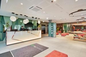 a lobby of a hotel with a man sitting at a counter at H+ Hotel Frankfurt Eschborn in Eschborn