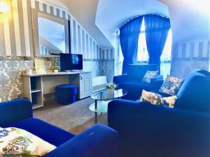 a living room with blue chairs and a tv at Boutique Hotel Royal in Nesebar
