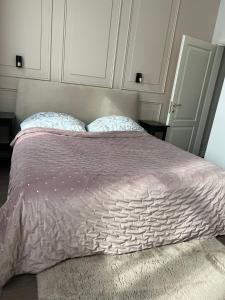 uma cama com um edredão roxo e duas almofadas em Old town apartment em Kaunas