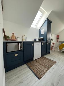 eine Küche mit blauen Schränken, einer Spüle und einem Geschirrspüler in der Unterkunft The Loft Curracloe, on Wexfords Coastal Scenic Route in Wexford