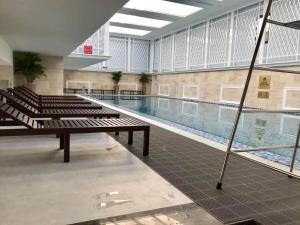 a swimming pool in a large building with benches at Luxury Homestay Vinhomes Dragonbay Hạ Long in Ha Long