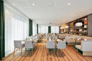 a restaurant with white chairs and tables and windows at H+ Hotel Frankfurt Eschborn in Eschborn