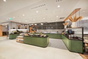 a large kitchen with green cabinets and a counter top at H+ Hotel Frankfurt Eschborn in Eschborn