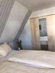 een slaapkamer met een wit bed en een spiegel bij Kathrin, Ferienwohnung in Schneverdingen