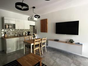kuchnia ze stołem i telewizorem na ścianie w obiekcie Enklawa Mielno przy plaży - Szklane apartamenty w mieście Mielno