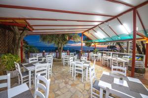 a restaurant with white tables and white chairs at Delight Beach Hotel in Dhërmi