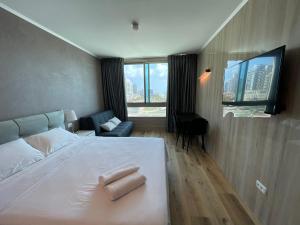 um quarto com uma cama branca e uma grande janela em Carmel Holiday Apartments em Netanya