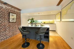 a kitchen with a counter with two stools and a brick wall at RWY Suite58 Luxury 2 Bed Apartment at Royal William Yard in Plymouth