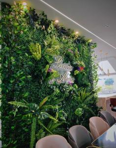 a green wall with plants in a room with chairs at Hôtel Restaurant Le Relais - Pau Nord in Lons