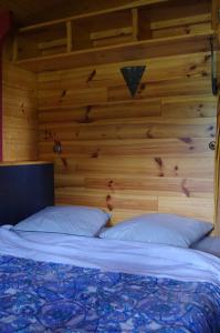 un lit dans une chambre avec un mur en bois dans l'établissement Camping La Bergerie, à La Chapelle-Achard