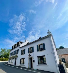 a white building with black windows on a street at Sur La Route Des Myrtilles in Gouézec