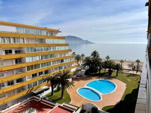 a hotel with two pools and palm trees and the ocean at SANTA BEACH in Roses